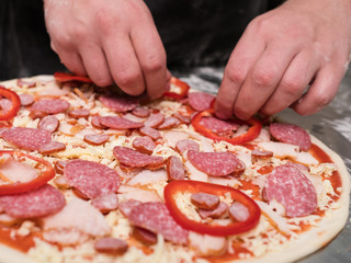Chef cooking pepperoni pizza and adding ingredients on top. Simple yet delicious traditional...