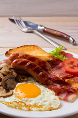 Traditional English or Irish breakfast: sausages, bacon, egg, mushrooms, tomatoes and toasts. Nutritious morning meal. vertical