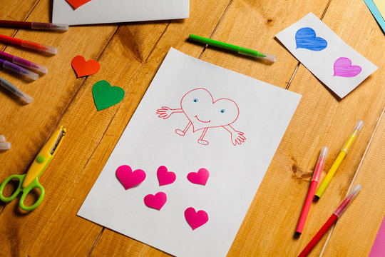 Child draws a heart. Little boy making a card for Valentine's Day.