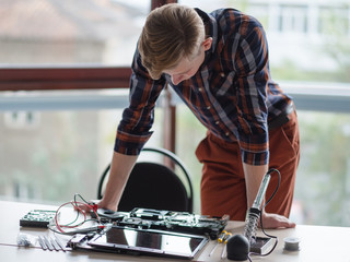 Computer engineer standing over a disassembled laptop. Science technology electronics design development