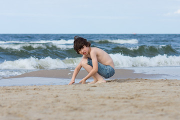 A guy in denim shorts is happy on the sandy beach of the sea.
