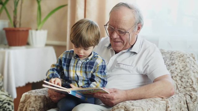 Nice little boy reading a book with his grandfather - Powered by Adobe
