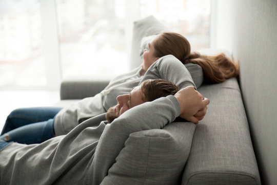 Relaxed Couple Asleep Resting Or Having Nap Sitting On Comfortable Sofa Enjoying Daytime Doze On Weekend, Calm Carefree Man And Woman Relaxing Sleeping Leaning On Couch In Cozy Living Room Together