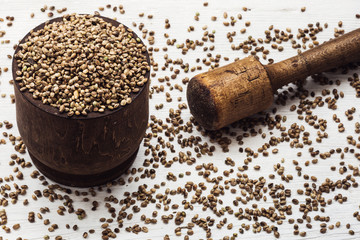 Hemp seeds in an old wooden mortar on a white background.