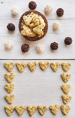 Homemade cookies with turmeric and flax seeds in the form of heart on white boards with a basket and tangles of vine.