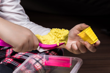 A child's hands playing with yellow magic sand and building, kneading at home. - 189382163