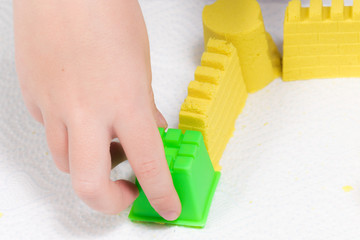 A child's hands playing with yellow magic sand and building, kneading at home. - 189382189
