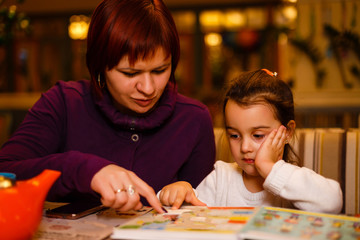 mother and daughter in a cafe read a book