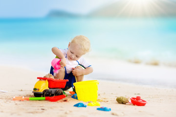Kids play on tropical beach. Sand and water toy.