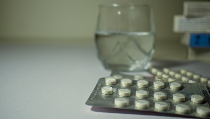 White pills with a blurred glass