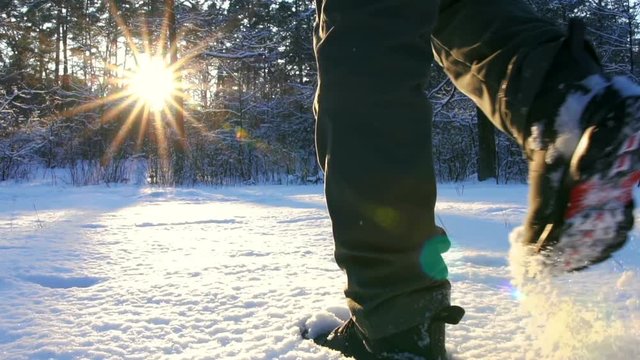 Hiking in the deep snow in winter. Close-up of feet walking in snowy mountain forest on sunset. Winter Journey Adventure.