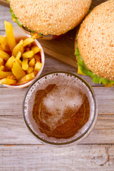 Glass of beer with burger and fries on wooden background. Beer and food concept. Ale and food. View from above, top, vertical