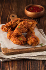 Fried crispy chicken nuggets with ketchup on wooden background.