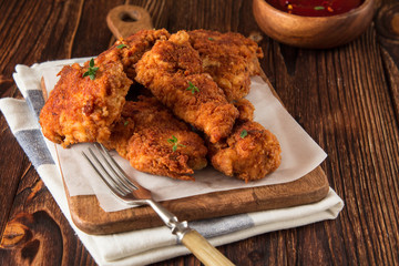 Fried crispy chicken nuggets with ketchup on wooden background.