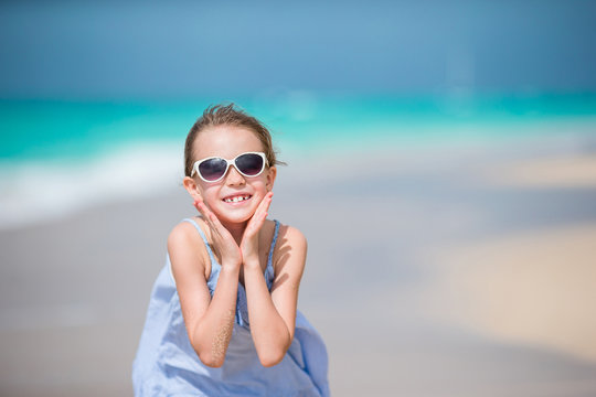 Portrait of happy adorablr kid looking at camera background beautiful sky and sea. Little girl in sunglasses smile and enjoy her vacation
