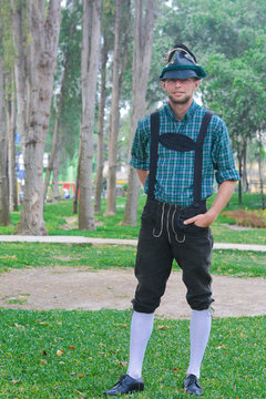 Young caucasian man wearing traditional bavarian clothes in the summer park.