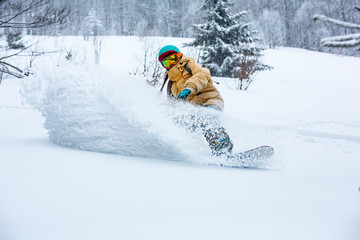 A snowboarder girl is riding down the hill. Powder day in mountains.