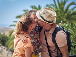 Fototapeta premium Travelling family of three people is kissing and hugging.