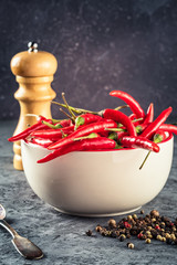 Red hot chilli pepper paprika in glass transparent bowl on stone table