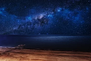 Abwaschbare Fototapete Nacht Nachtsternenklarer Himmel über dem Strand mit einem Pier.