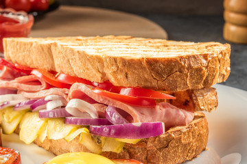 Fried egg fried in slice of red sweet pepper and sandwich with ham and seasonal vegetables on white plate