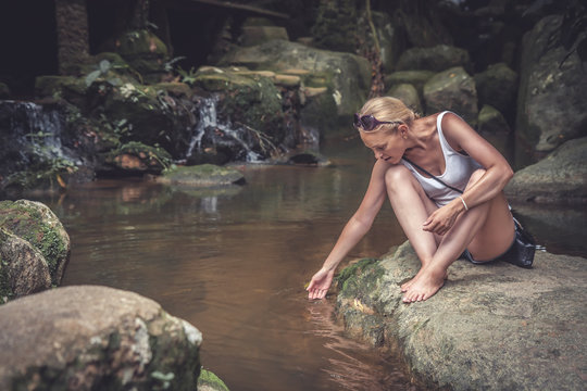 Beautiful woman tourist relaxing nerby waterfall  during her travel holidays in tropical country 
