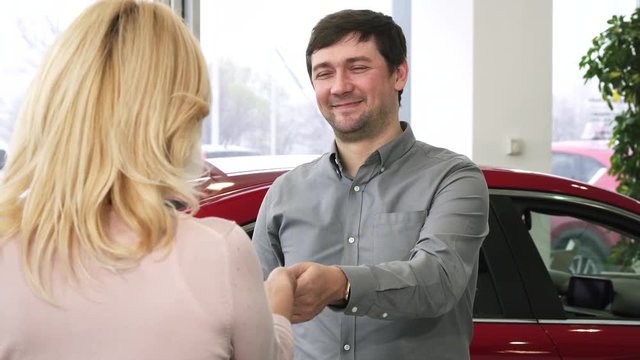 Mature cheerful man smiling joyfully giving car keys of a new auto he just bought to his wife present gift celebrating congratulations anniversary love family relationships travel surprise.
