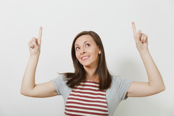 Close up young attractive smiling brunette caucasian housewife in apron isolated on white background. Beautiful housekeeper woman pointing index fingers up looking up. Copy space for advertisement.