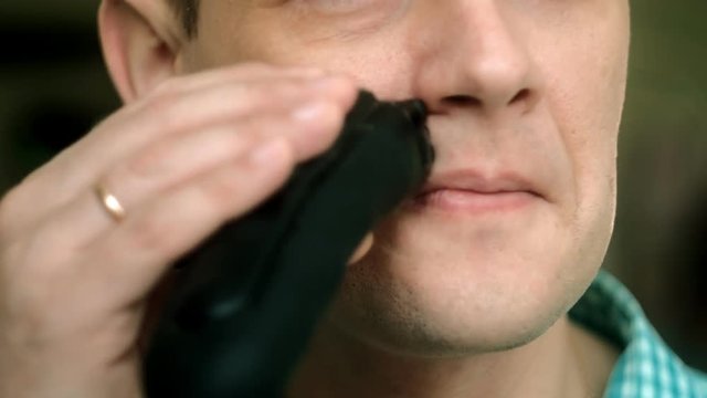 Man shaving beard with electric shaver. Check shaving swiping your finger on the cheek. Closeup.