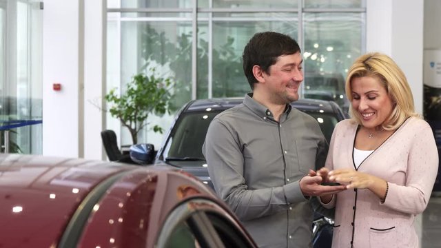 Gorgeous happy mature woman smiling embracing her husband after receiving car keys to a new auto dealership celebrating anniversary congratulate happiness love marriage