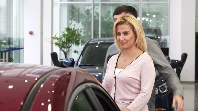 Mature man covering eyes of his wife at the dealership presenting her a new car as a gift happiness car keys ownership driving emotions love family travel driving.