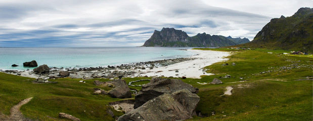 Autumn panorama of Uttakliev beach on the Lofoten islands in cloudy weather. Rocks in azure ocean....