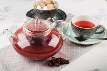 Serving table for breakfast, red tea in teapot and cup on a white table