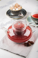 Serving table for breakfast, red tea in teapot and cup on a white table