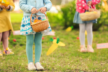 Little girl with basket of colorful eggs in park. Easter hunt concept