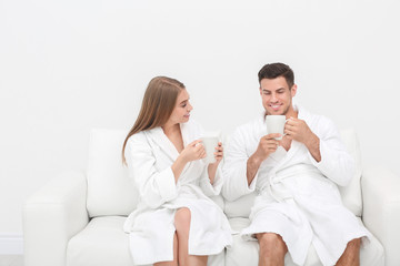 Young loving couple in bathrobes relaxing on sofa