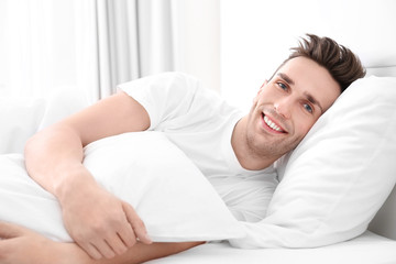 Young man lying on white pillow at home