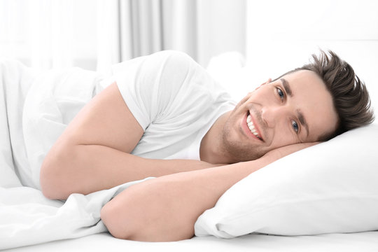 Young man lying on white pillow at home