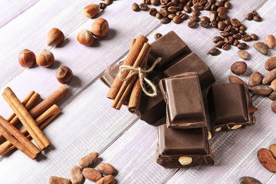 Composition with chocolate, cocoa beans and cinnamon on wooden background