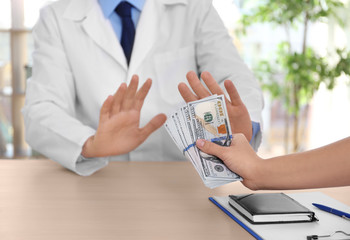 Male doctor refusing to take bribe from woman at workplace