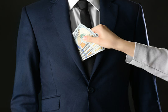 Woman putting bribe in businessman's pocket, closeup