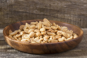 Toasted peanuts on wooden background - Arachis hypogaea