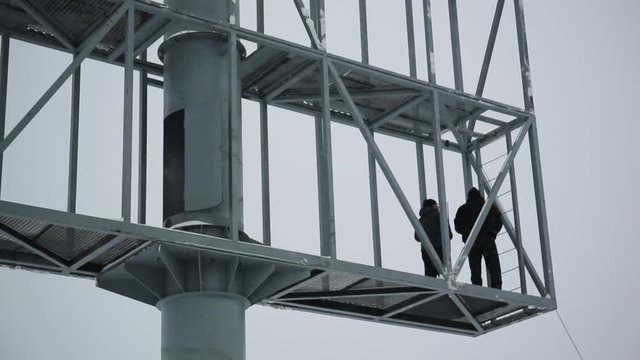 The tower crane lifts the white plate. Crane building a Billboard. The construction of the Billboard in the winter time