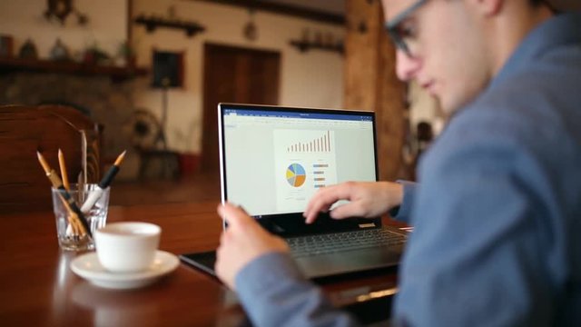 Young man shopping on the internet and paying with credit card. Handsome freelancer businessman in glasses replenish his stock exchange account with laptop via web application. Business concept.