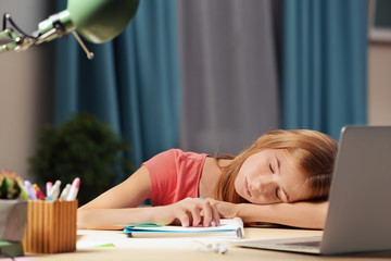 Teenage girl falling asleep while doing homework at table