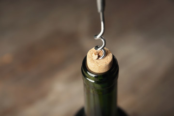 Opening bottle of wine with corkscrew, closeup