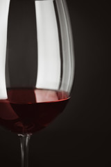 Naklejka na ściany i meble Glass of red wine on black background, closeup
