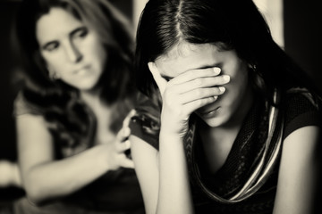 Mother comforts her crying teenage daughter
