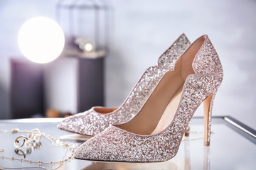 Beautiful high heeled shoes and jewelry on table