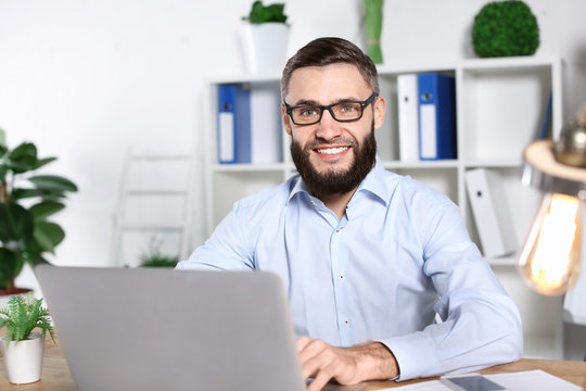 Portrait of handsome bearded man with laptop indoors